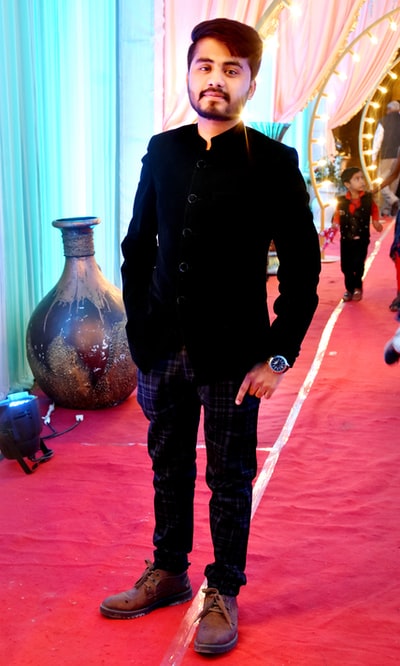 Dressed in a black jacket and blue denim jeans man standing beside the transparent plastic bottle
